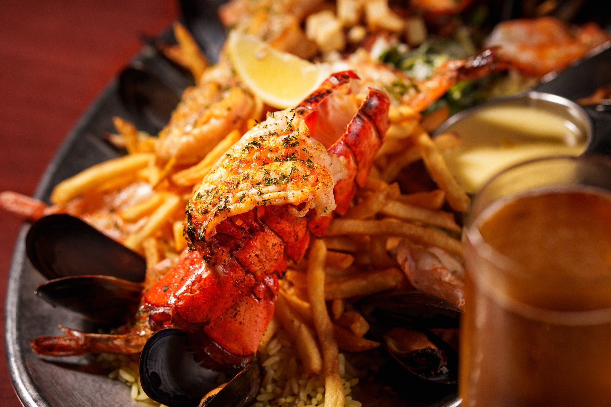 Queue de homard, moules et frites sur un plateau, bière en arrière-plan